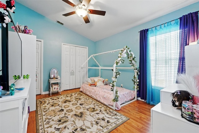 bedroom featuring a ceiling fan, visible vents, light wood-type flooring, two closets, and lofted ceiling
