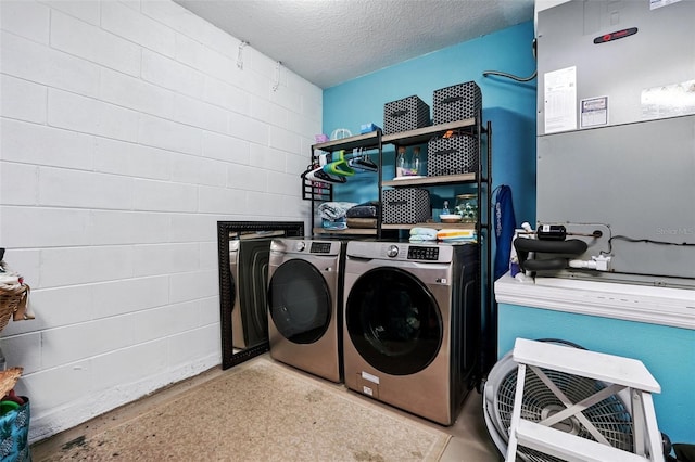 washroom with laundry area, washer and clothes dryer, a textured ceiling, and heating unit