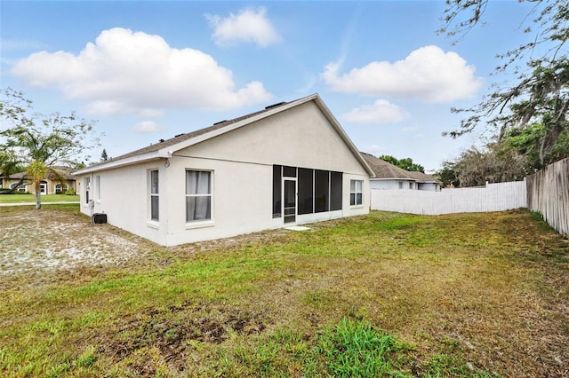 back of house featuring a lawn, fence, and stucco siding