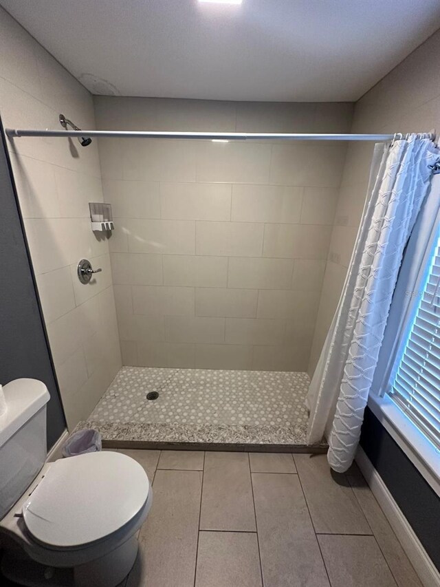 8702 El Portal Dr, Tampa, FL 33604 - bathroom with tiled shower, toilet, and tile patterned flooring