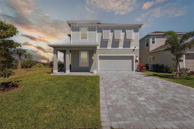 2476 Kamin Dr, Melbourne, FL 32940 - view of front of house with a front yard, a garage, decorative driveway, central AC, and stucco siding