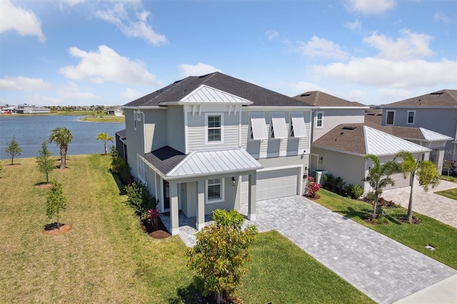 2476 Kamin Dr, Melbourne, FL 32940 - view of front of home with decorative driveway, stucco siding, a standing seam roof, an attached garage, and a water view