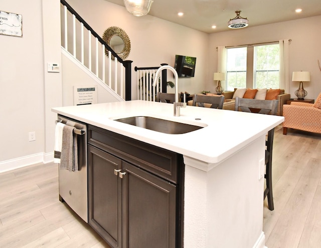kitchen featuring a sink, a kitchen island with sink, light wood finished floors, and dishwasher