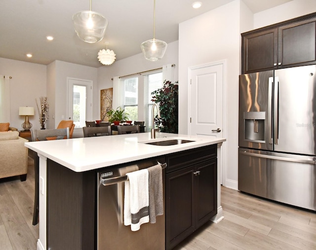 kitchen with open floor plan, a kitchen bar, a sink, light wood finished floors, and stainless steel appliances