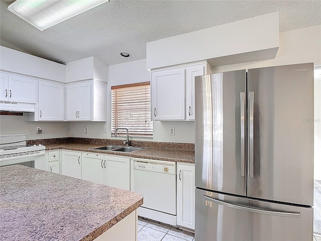 kitchen featuring a sink, a textured ceiling, under cabinet range hood, and white appliances