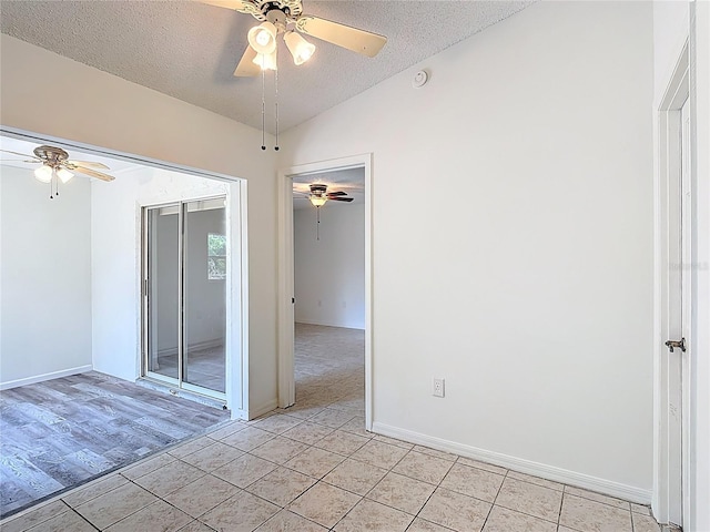 spare room featuring a ceiling fan, a textured ceiling, baseboards, and lofted ceiling