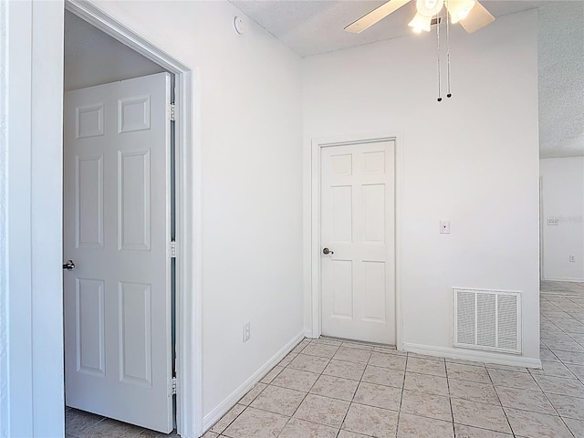 empty room with ceiling fan, a textured ceiling, baseboards, light tile patterned floors, and visible vents