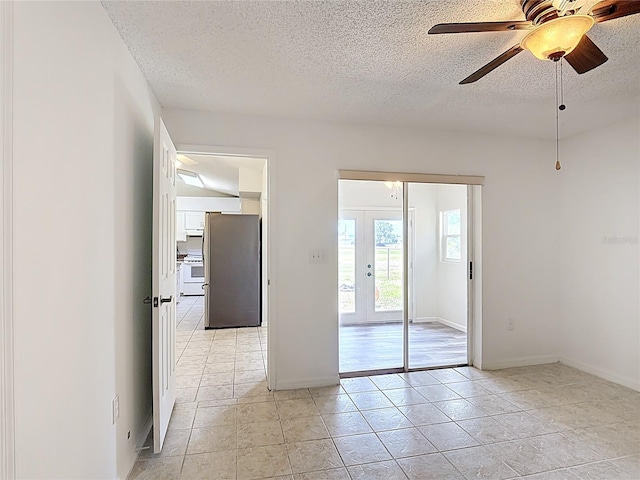 spare room featuring baseboards, a ceiling fan, a textured ceiling, and french doors