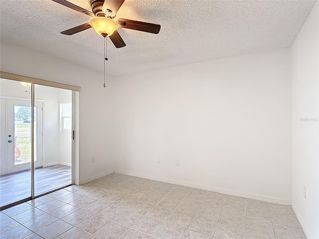 spare room featuring baseboards, a ceiling fan, a textured ceiling, and light tile patterned flooring
