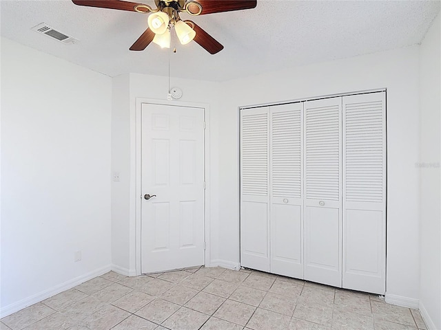 unfurnished bedroom featuring light tile patterned floors, a closet, a textured ceiling, and visible vents
