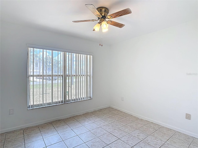 empty room with light tile patterned flooring, ceiling fan, and baseboards