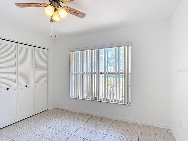 unfurnished bedroom with baseboards, ceiling fan, a closet, and light tile patterned flooring