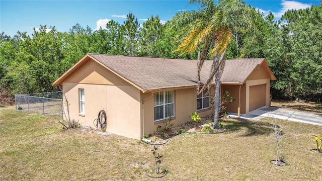 ranch-style home featuring a front lawn, stucco siding, driveway, and fence