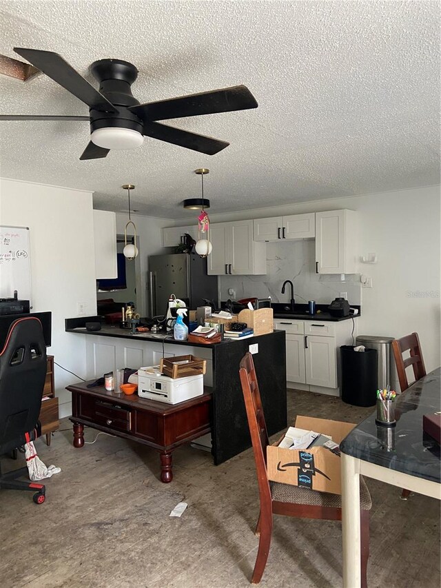 225 Ronnie Cir, Orlando, FL 32811 - kitchen with a textured ceiling, refrigerator, ceiling fan, dark countertops, and white cabinets
