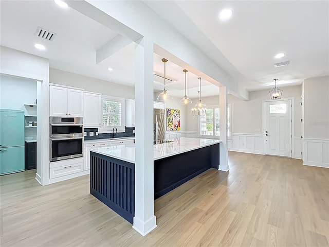 kitchen featuring a sink, light wood-style floors, stainless steel appliances, and visible vents