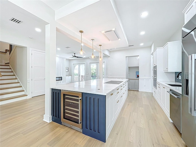 kitchen with beverage cooler, white cabinetry, visible vents, and stainless steel appliances