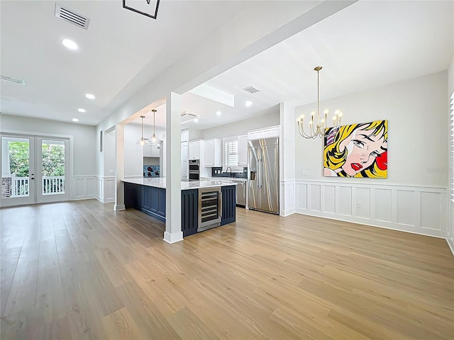 kitchen featuring a decorative wall, beverage cooler, open floor plan, a chandelier, and stainless steel appliances