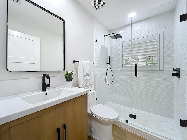 bathroom featuring toilet, visible vents, a shower stall, and vanity