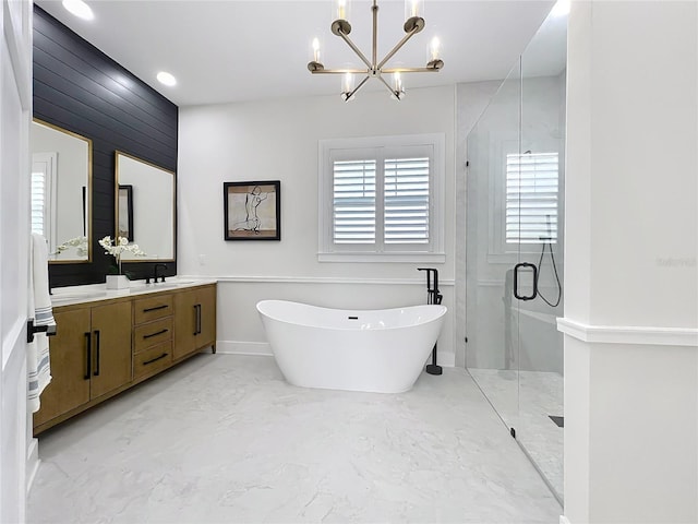 full bath with a freestanding bath, a stall shower, a notable chandelier, vanity, and marble finish floor