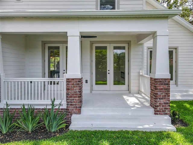 doorway to property with covered porch, brick siding, and french doors
