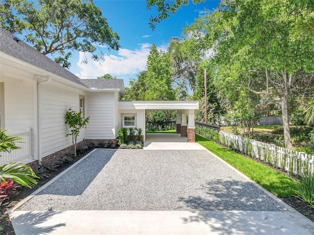 exterior space with fence, a carport, and driveway