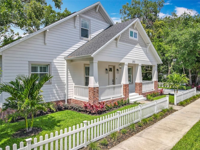 view of front facade featuring fence private yard, a shingled roof, and covered porch