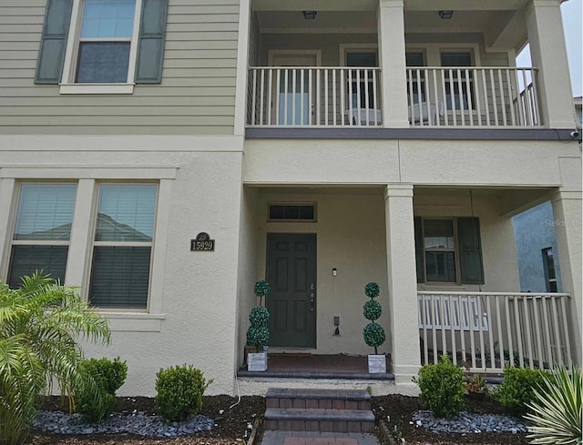 property entrance with stucco siding and a balcony
