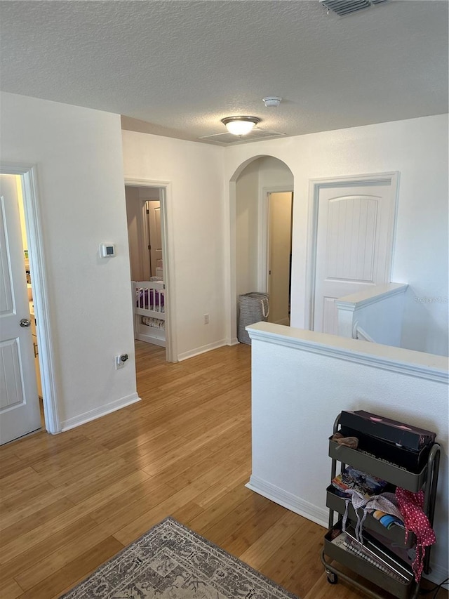 15929 Moonlight Bay St, Winter Garden, FL 34787 - hallway with arched walkways, light wood finished floors, and a textured ceiling