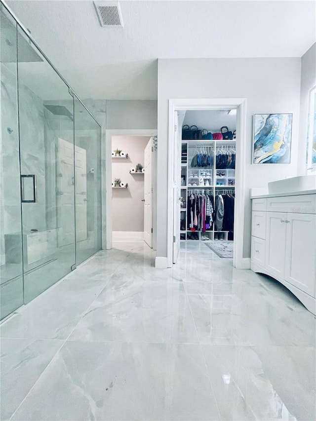 247 Whispering Pines Way, Davenport, FL 33837 - bathroom featuring marble tiled floors, a shower stall, a spacious closet, baseboards, and vanity