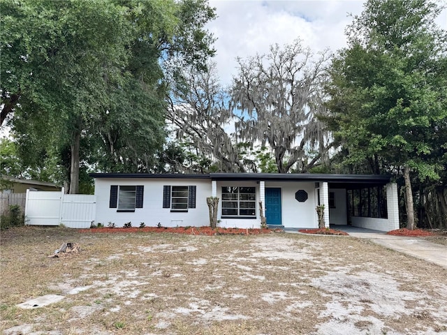 single story home featuring concrete driveway, fence, and a carport