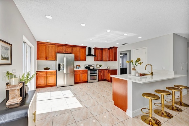 1176 Epson Oaks Way, Orlando, FL 32837 - kitchen featuring wall chimney range hood, appliances with stainless steel finishes, a sink, a kitchen breakfast bar, and a peninsula