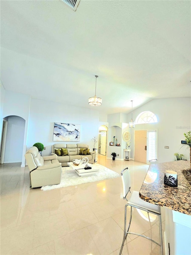 2346 Lily Pad Ln, Kissimmee, FL 34743 - living room featuring arched walkways, vaulted ceiling, and light tile patterned flooring