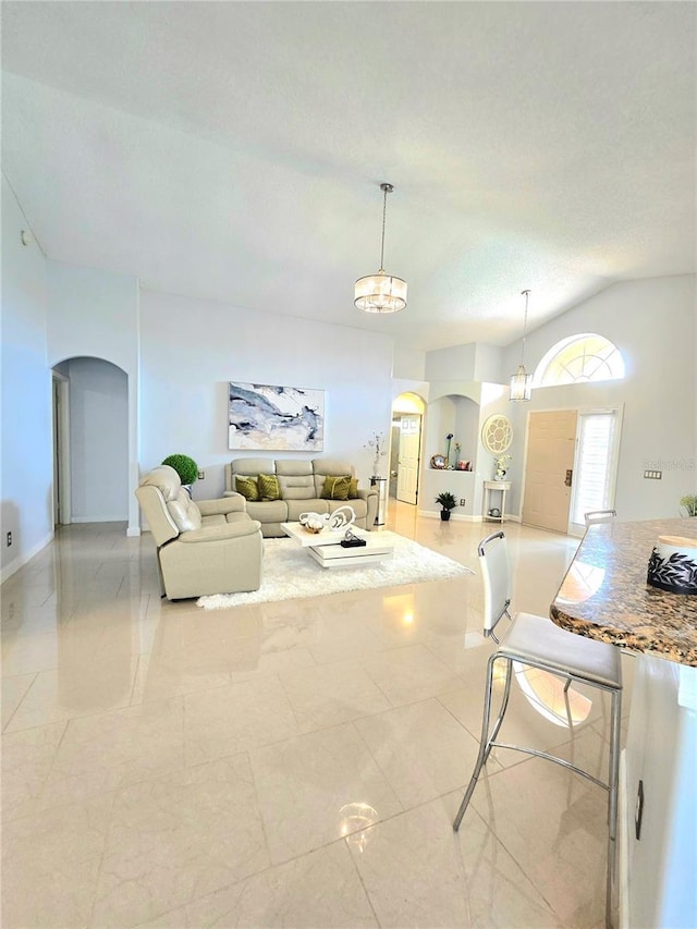 2346 Lily Pad Ln, Kissimmee, FL 34743 - living area featuring arched walkways, tile patterned flooring, a chandelier, and vaulted ceiling