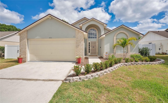 view of front of home with a front lawn, stucco siding, brick siding, an attached garage, and driveway