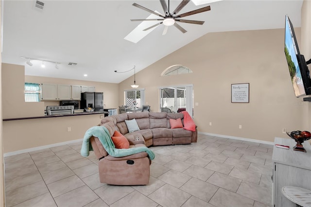 living area featuring visible vents, ceiling fan, a skylight, and high vaulted ceiling