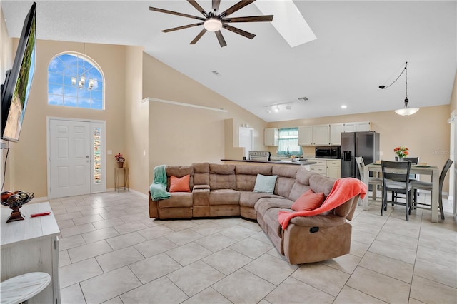 living room featuring light tile patterned floors, high vaulted ceiling, ceiling fan with notable chandelier, and visible vents