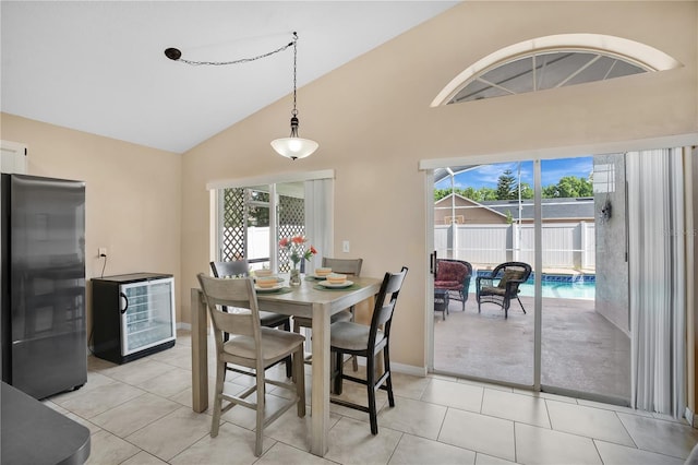 dining room featuring baseboards, wine cooler, light tile patterned floors, and high vaulted ceiling