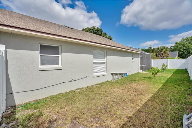 view of property exterior with a yard, a fenced backyard, glass enclosure, and stucco siding