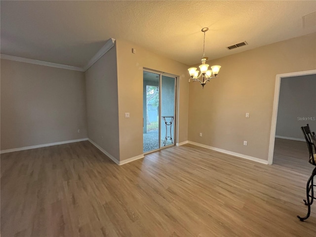 spare room featuring light wood finished floors, a chandelier, and visible vents