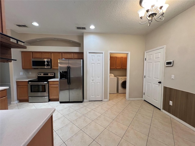 kitchen featuring visible vents, appliances with stainless steel finishes, independent washer and dryer, and a notable chandelier