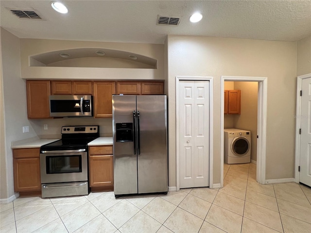 kitchen featuring washer / clothes dryer, appliances with stainless steel finishes, brown cabinetry, and visible vents