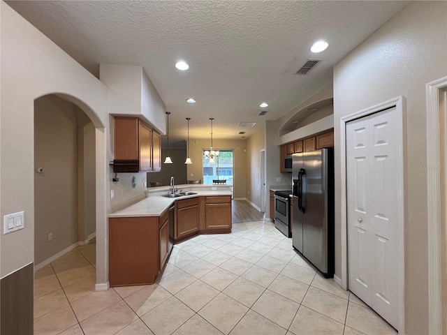 kitchen with brown cabinetry, visible vents, a sink, a peninsula, and stainless steel appliances