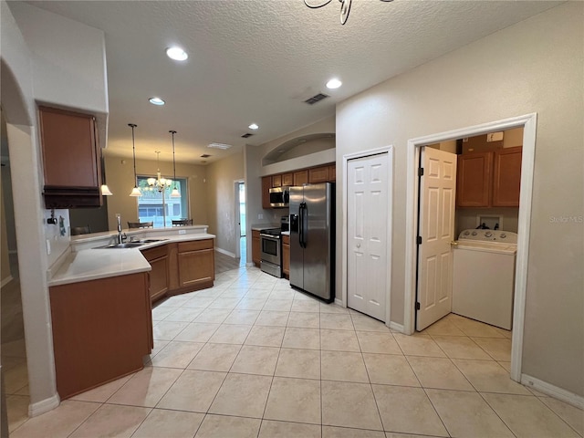 kitchen with visible vents, appliances with stainless steel finishes, a sink, a peninsula, and washer / dryer