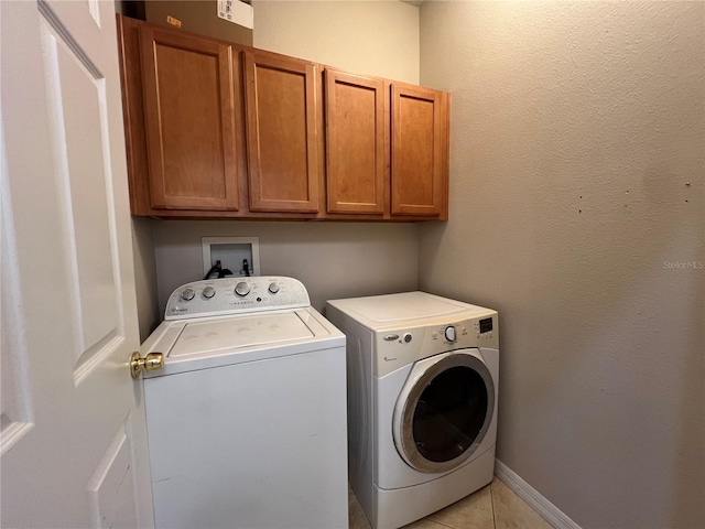 clothes washing area featuring cabinet space, light tile patterned flooring, and washer and dryer