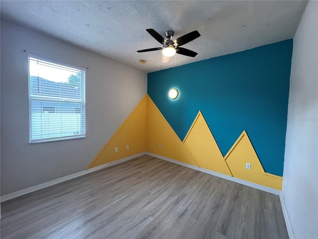 unfurnished room featuring a textured ceiling, ceiling fan, baseboards, and wood finished floors