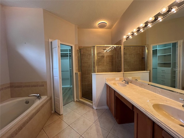 full bath with a textured ceiling, a shower stall, a sink, tile patterned floors, and a spacious closet