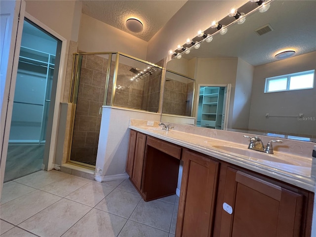 full bath with a textured ceiling, visible vents, tile patterned flooring, a shower stall, and a sink