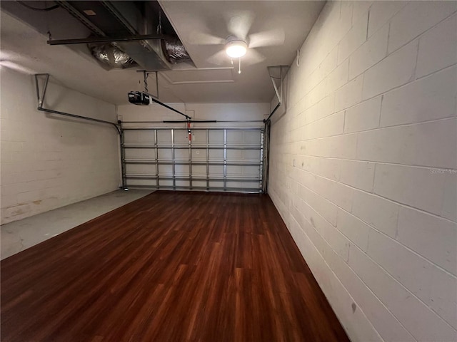 garage featuring concrete block wall and a garage door opener