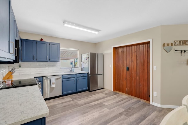 kitchen featuring backsplash, blue cabinets, appliances with stainless steel finishes, light wood-type flooring, and light countertops