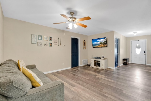 living room with a ceiling fan, baseboards, visible vents, and wood finished floors